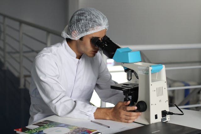 person wearing a hair net using a microscope