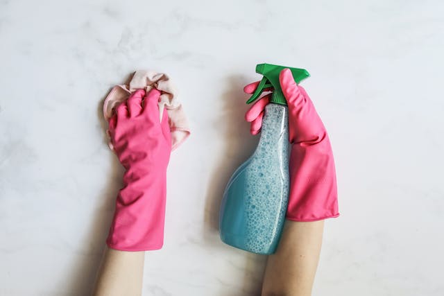person-wearing-pink-gloves-using-a-cleaning-cloth-and-a-cleaning-spray-to-clean-a-counter