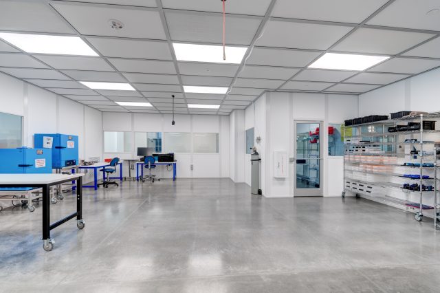 Clean, modern laboratory workspace with bright lighting, workstations, and organized shelving.