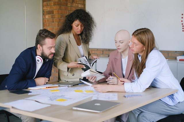 a-group-of-four-people-collaborating-at-a-table-with-documents-and-a-laptop