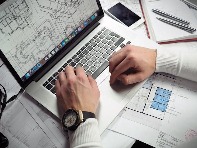 person-using-a-laptop-to-look-at-blueprints