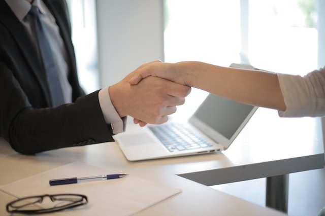 two-people-shaking-hands-over-desk